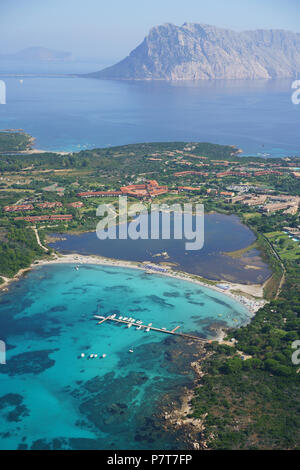 LUFTAUFNAHME. Kleine geschützte Bucht, die durch eine Sandbank von einem Teich getrennt ist. Capo Coda Cavallo, Provinz Sassari, Sardinien, Italien. Stockfoto