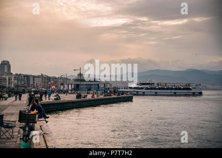 Izmir, Türkei - Oktober 28, 2017: Blick über Izmir Alsancak Fähre und Personen, die sich in der Nähe von Waters Edge mit Wetter sitzen. Stockfoto