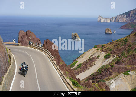 Fahrer auf einem Dual-Sport-Motorrad auf einer corniche mit Blick auf das Mittelmeer. Masua, Provinz Südsardinien, Sardinien, Italien. Stockfoto