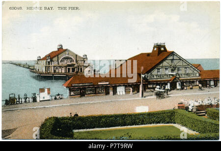 Hand - farbige Postkarte Foto 1910-1928 Übersicht Die dritte Herne Bay Pier, die 1899 erbaut wurde. Die Karte ist 15 August 1928 eingesandt, und die hölzerne Theater Eingang Gebäude, in diesem Foto gesehen, brannte am 9. September 1928. Aber das Foto war fast sicher vor 1914 aufgegriffen, die vom Stil der Kostüm- und kremserfahrt im Vordergrund. Grand Pier Pavillon (großes Gebäude am Pier) wurde gebaut 1910. Postmarked 1928; Foto wahrscheinlich früher 10 3 Herne Bay Pier 1910-28 018 genommen Stockfoto