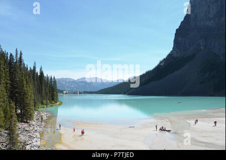 LAKE LOUISE, AB/KANADA - 26. JULI 2017: Touristen das Ende von Lake Louise erkunden gegenüber dem Fairmont Chateau Lake Louise Hotel. Stockfoto