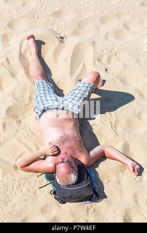 Bournemouth, Dorset, Großbritannien. Juli 2018. Wetter in Großbritannien: Ein weiterer heißer sonniger Tag, an dem die Hitzewelle andauert und Tausende von Sonnenanbetern an die Küste gehen, um die Sandstrände in Bournemouth an der Südküste zu genießen. Mann zum Sonnenbaden am Strand - von oben betrachtet. Credit: Carolyn Jenkins/Alamy Live News Stockfoto