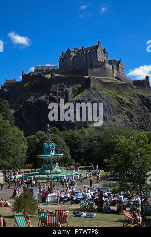 Edinburgh, Schottland, Großbritannien. Vom 8. Juli 2018. Ross Brunnen, West Princes Street Schalter Gärten am Tag, Massen von Familien und Touristen in der Sonne zu sehen, die zirkusvorstellungen und Edinburgh's School Pipe Band und Baden im Brunnen Wasser, das im Jahr 2010 geschaltet wurde. Stockfoto