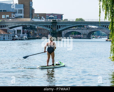 Themse, Hampton Wick, London, England, Vereinigtes Königreich, 8. Juli 2018. UK Wetter: Leute genießen, sich auf der Themse an einem Sonntag Morgen in der heißen Sonne Hitzewelle. Eine ältere Frau Paddle Boarding in Richtung Kingston Bridge Stockfoto