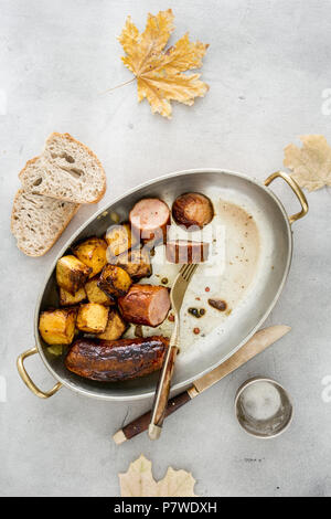 Gebratene Würstchen mit Kürbis in der Pfanne auf einem hellen Oberfläche, Ansicht von oben Stockfoto