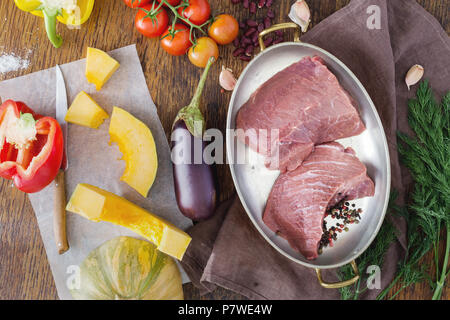 Frisches Rinderfilet mit Gemüse, Ansicht von oben. Zutaten für das Kochen von Fleisch mit Gemüse auf einem Holztisch. Stockfoto