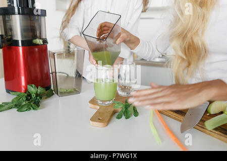 Mutter und Tochter kochen detox Drink von Sellerie, Apfel und Minze in der Küche zu Hause. Gesunder Lebensstil Konzept Stockfoto