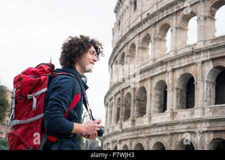 Hübscher junger Tourist Mann mit Kamera und Rucksack, die Bilder von Kolosseum in Rom, Italien. Jungen Touristen, die Bilder von Kolosseum Stockfoto