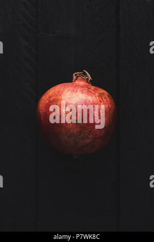 Flach reifer Granatapfel Obst auf schwarzem Holz- vintage Hintergrund. Ansicht von oben mit der Kopie. Stockfoto