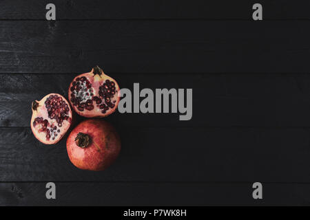 Flach reifer Granatapfel Obst auf schwarzem Holz- vintage Hintergrund. Ansicht von oben mit der Kopie. Stockfoto