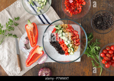 Schwarz Quinoa, Kichererbsen, Paprika, Gurken, Tomaten und Petersilie auf Holztisch, Ansicht von oben. Sommer vegetarisch Salat mit Zutaten zum Kochen veget Stockfoto