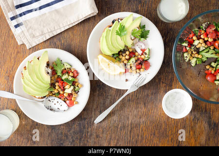 Leckere und gesunde vegetarische Kost. Salat von schwarzen Quinoa, Kichererbsen und Gemüse mit Avocado bruschetta auf einem Holztisch mit Limonade, Ansicht von oben Stockfoto