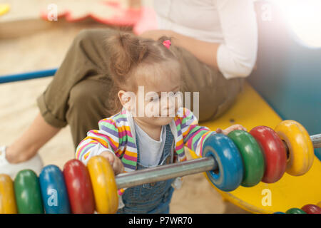 Ein kleines Mädchen mit zwei Schwänze in einem gestreifte Bluse spielt eine Sommer sonnigen Tag auf dem Spielplatz Sommer Familie Freizeit Stockfoto