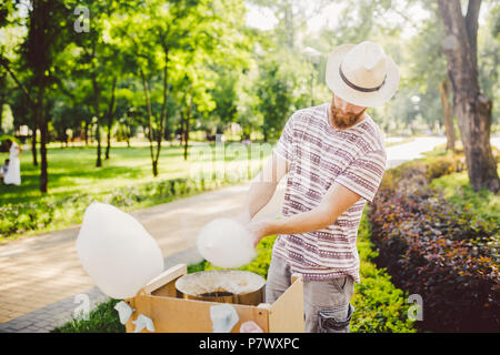 Foto Thema Small Business kochen Süßigkeiten. Ein junger Mann mit einem Bart von einem kaukasischen Trader in den Hut der Eigentümer der Steckdose macht Zuckerwatte, Fee Stockfoto