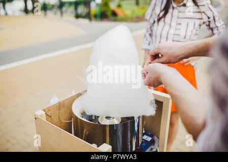 Thema ist eine Familie Small Business kochen Süßigkeiten. Hände close-up Junge Frau Händler, Eigentümer der Steckdose macht eine Zuckerwatte, fairy Glasschlacke oder Baumwolle cand. Stockfoto