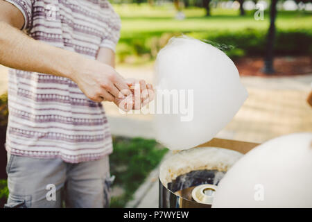 Thema ist eine Familie Small Business kochen Süßigkeiten. Hände close-up ein junges Männchen Ladenbesitzer Holding ein Kaufmann macht Zuckerwatte, fairy Glasschlacke oder Baumwolle ca Stockfoto