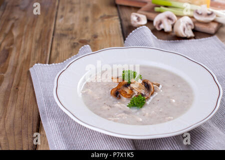 Rahm Suppe mit Pilzen und Hähnchenfilet und frischer Petersilie Grüns. In einer weißen Platte. Braun Holz- Hintergrund. Freier Platz für Text. Super Essen. Stockfoto