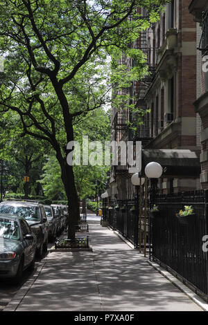 Auf der Suche nach W. 111 Straße Bürgersteig in der Upper West Side von New York City, die aus rotem Ziegelstein Wohnhäuser aus der Zeit vor dem Krieg, hohen Bäumen, angenehm. Stockfoto