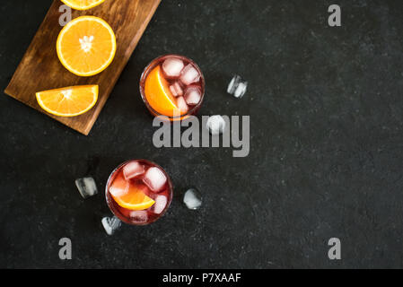 Negroni Cocktail mit Orangen und Eis. Hausgemachte klassische Negroni Cocktail und Zutaten auf schwarzem Hintergrund, kopieren. Stockfoto