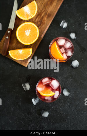 Negroni Cocktail mit Orangen und Eis. Hausgemachte klassische Negroni Cocktail und Zutaten auf schwarzem Hintergrund, kopieren. Stockfoto