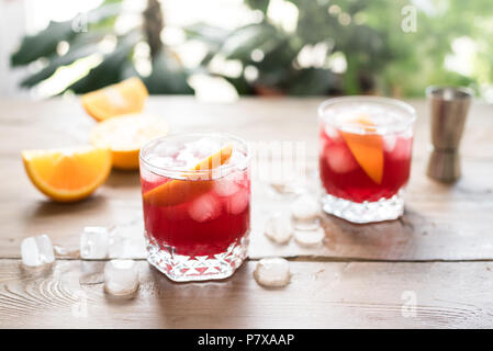 Negroni Cocktail mit Orangen und Eis. Hausgemachte klassische Negroni Cocktail und Zutaten auf Holztisch, kopieren. Stockfoto