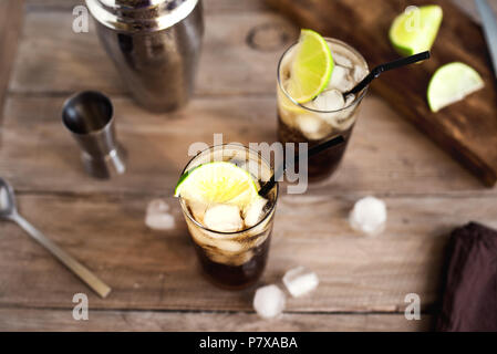 Rum und Cola Cuba Libre trinken mit Kalk und Eis auf rustikalen Holztisch Stockfoto