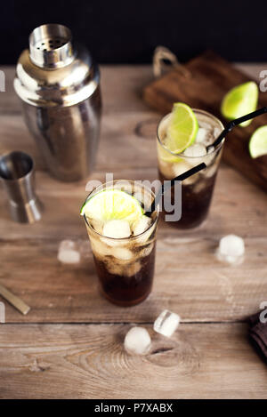 Rum und Cola Cuba Libre trinken mit Kalk und Eis auf rustikalen Holztisch Stockfoto