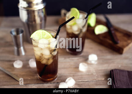 Rum und Cola Cuba Libre trinken mit Kalk und Eis auf rustikalen Holztisch Stockfoto