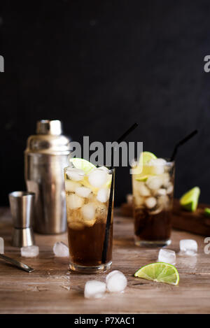 Rum und Cola Cuba Libre trinken mit Kalk und Eis auf rustikalen Holztisch Stockfoto