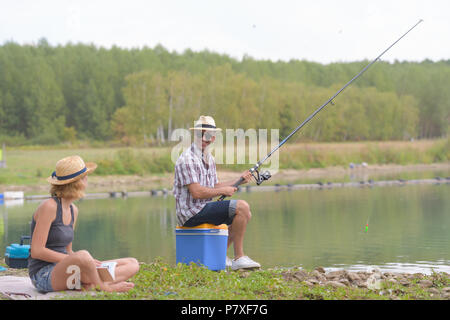 Glückliches Paar Angeln am Ufer des Teiches Stockfoto