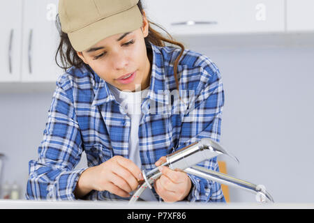 Weibliche Klempner Arbeiten am Waschbecken mit einem Schraubenschlüssel Stockfoto