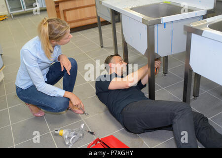 Junge Frau von klempner zur Festsetzung Spüle suchen Stockfoto