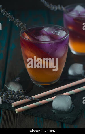 Pfirsich Aperol Spritz Schichten mit Pfirsich und Lavendel Wasser auf Holzschreibtisch. Stockfoto