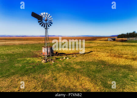 Einzelne historische selbst Wicklung Wind Mill Pumpen von Wasser in abgelegenen Rinderfarm auf trockene Ebene des Lake George Land in regionalen NSW outback an einem sonnigen Tag Stockfoto