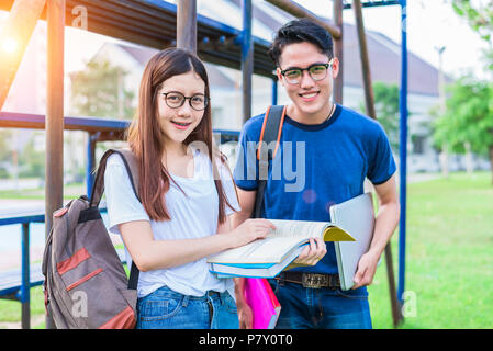 Zwei Asiatische junge Hochschule die Menschen über das Lesen Buch und mit Laptop für Suche diskutieren und Wissen lernen. Bildung und Freundschaft Konzept. Happin Stockfoto