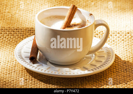 Tasse Kaffee mit Zimtstangen auf sackleinen Stockfoto