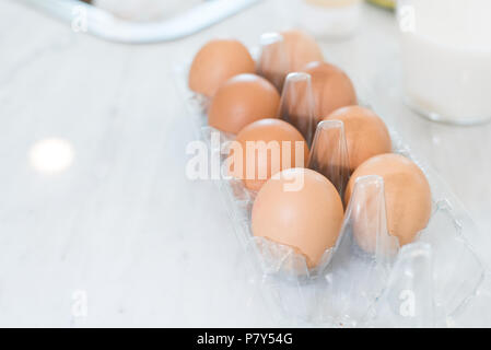 Nahaufnahme von Dutzend Eier auf weißen Tisch zum Kochen in der Küche zubereiten. Dessert Zutaten und Lebensmittel Konzept. Stockfoto