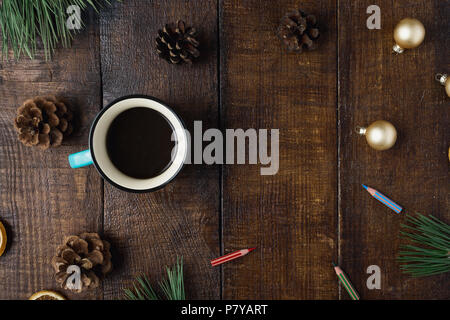 Weihnachtsferien Zusammensetzung auf braunem Holz- Hintergrund mit Tasse Kaffee, Tannenzapfen, Weihnachtskugeln, Buntstifte und Weihnachtsbaum branche Stockfoto