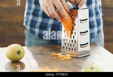 Gesunde Ernährung Konzept. Man Frühstück Vorbereiten von Salat von Karotten mit Apfel Stockfoto