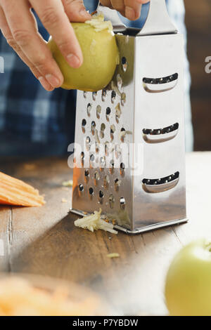 Gesunde Ernährung Konzept. Man Frühstück Vorbereiten von Salat von Karotten mit Apfel Stockfoto