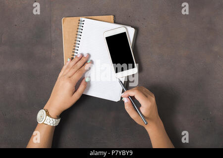 Frauen schreiben in einem Notebook am Arbeitsplatz. Flach, Ansicht von oben. Konzept feminine Arbeitsplatz Stockfoto
