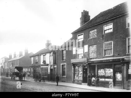 Englisch: Oxford Road, Reading. Nordseite, 1902. Nr. 66; Nr. 58; Nr. 56; Nr. 54; die Ecke von Thorn Straße; Nr. 52a (Charles Shepherd, Einkaufsmöglichkeit); Nr. 52 (Frank Thake, signwriter); Nr. 50; Nr. 48 (R. LLoyd und Sohn, Trafiken, mit Vorzeichen für Powell und Hurlock oben); der Eingang zu Brick Court; Nr. 46 (Henry Irwin, kragen Wäsche). Ein planwagen wartet an der Ecke von Thorn Straße. Eine Dame mit einem flechtwerk Pram spricht mit der Dame am Kragen Wäscheservice. 1900-1909: Fotografie von Walton Adams. 1902 298 Oxford Road, Reading, 1902 Stockfoto