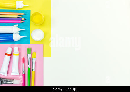 Schule stationäre Punkte auf weißem Schreibtisch. Buntstifte, Farben, Pinsel und Album farbiges Papier Stockfoto