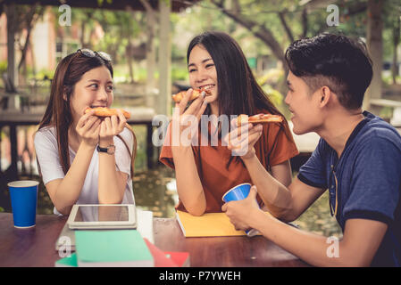 Jungen asiatischen Menschen feiern mit Pizza in der Hand. Essen und Freundschaft Konzept. Lebensstile Thema Stockfoto