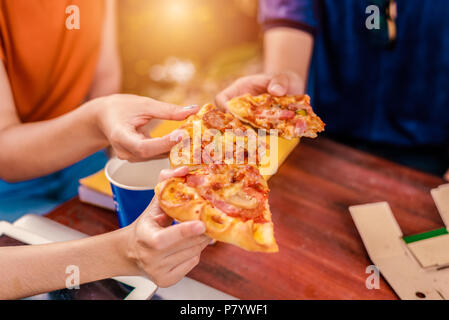 Die Menschen feiern mit Pizza in der Hand. Essen und Freundschaft Konzept. Lebensstile Thema Stockfoto