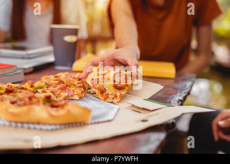 Die Menschen feiern mit Pizza in der Hand. Essen und Freundschaft Konzept. Lebensstile Thema Stockfoto