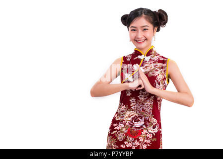 Junge Asiatische Schönheit Frau tragen Cheongsam und Segen oder Gruß Geste in Chinese New Year Festival Event auf isolierten weißen Hintergrund. Urlaub Stockfoto