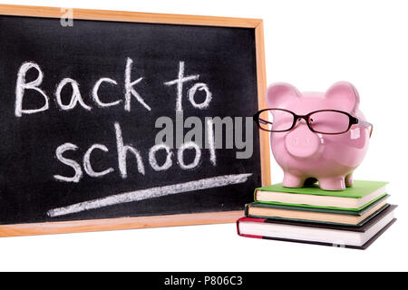 Rosa Sparschwein mit Brille stehen auf einem kleinen Stapel Lehrbücher neben einer kleinen Tafel mit zurück in die Schule. Auf weiß isoliert. Stockfoto