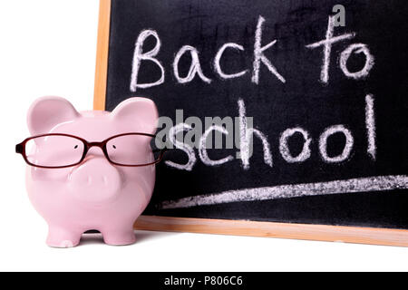 Rosa Sparschwein mit Brille vor einer kleinen Tafel stehend mit zurück in die Schule. Stockfoto