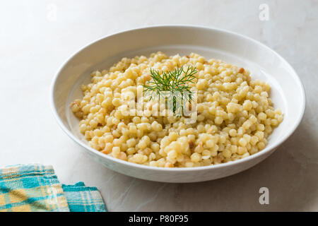 Gekochten Couscous mit Dill, serviert in weiße Platte/Türkischen Kuskus. Traditionelle biologische Lebensmittel. Stockfoto